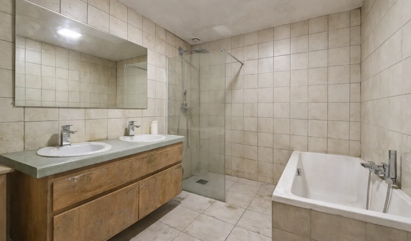 Before bathroom remodeling showing outdated tile, old vanity, and worn finishes in Dallas home.