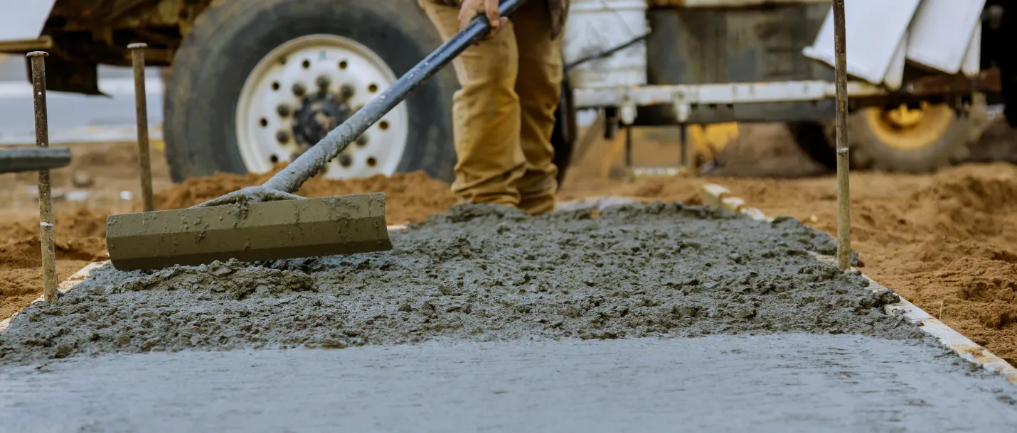 Concrete worker leveling fresh cement for residential walkway or patio installation