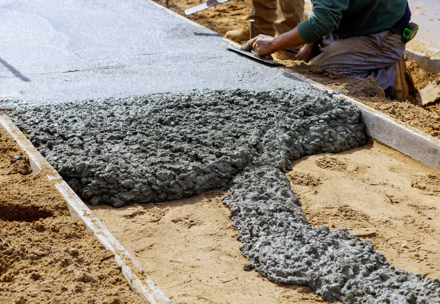 Concrete contractor pouring and leveling fresh concrete for driveway foundation project in Dallas