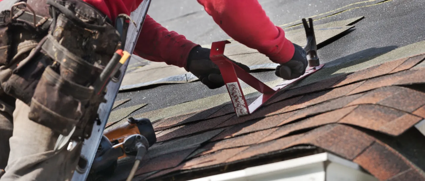 Contractor installing asphalt roof shingles on residential home during roofing project in Dallas TX